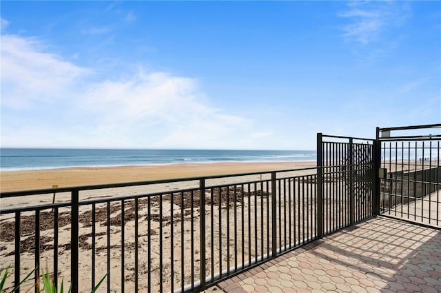 balcony with a water view and a view of the beach