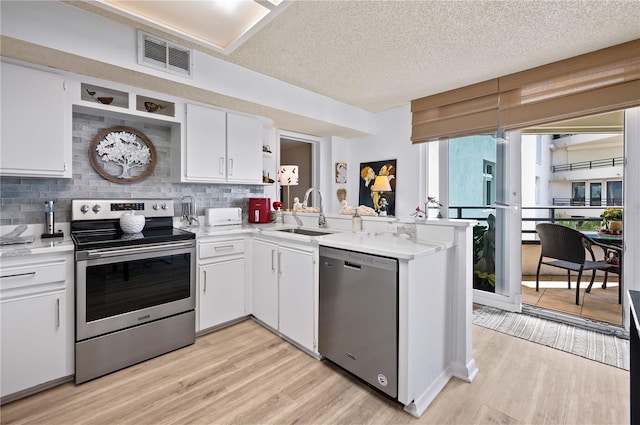 kitchen featuring white cabinetry, sink, kitchen peninsula, stainless steel appliances, and light wood-type flooring