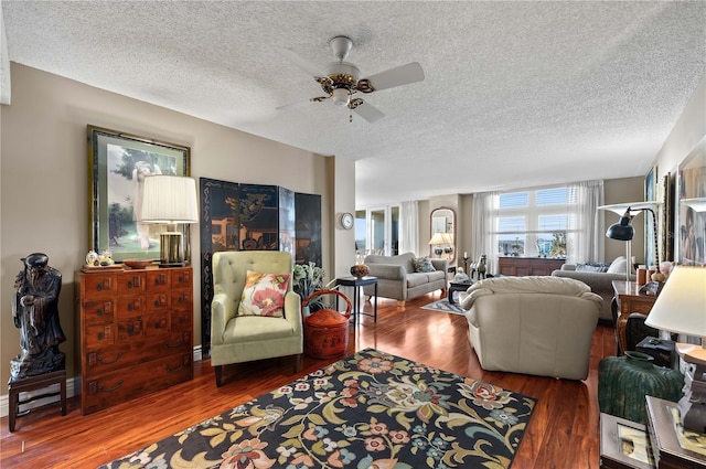 living room featuring wood-type flooring, ceiling fan, and a textured ceiling