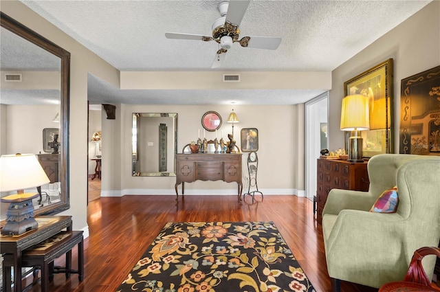 sitting room with ceiling fan, dark hardwood / wood-style floors, and a textured ceiling