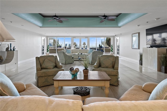 living room with a tray ceiling and ceiling fan