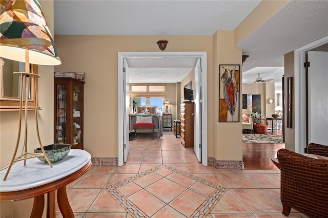 hallway with a textured ceiling and light tile patterned floors