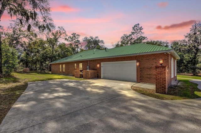 property exterior at dusk with a garage and a lawn