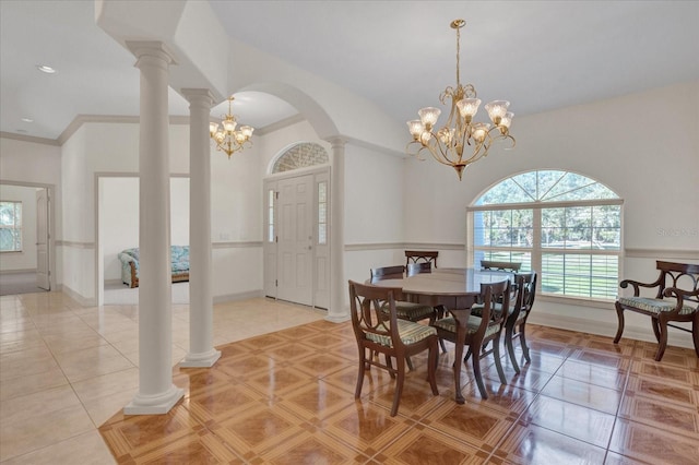 dining area with crown molding, light tile patterned floors, a notable chandelier, and decorative columns