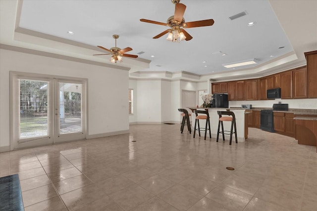 kitchen with a center island, a tray ceiling, a breakfast bar area, and black appliances