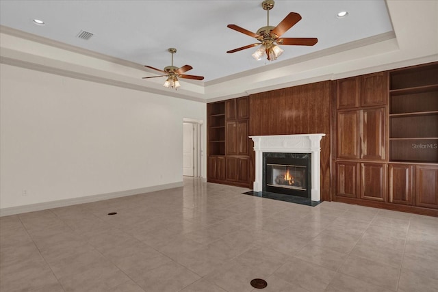 unfurnished living room with a high end fireplace, a raised ceiling, and ceiling fan