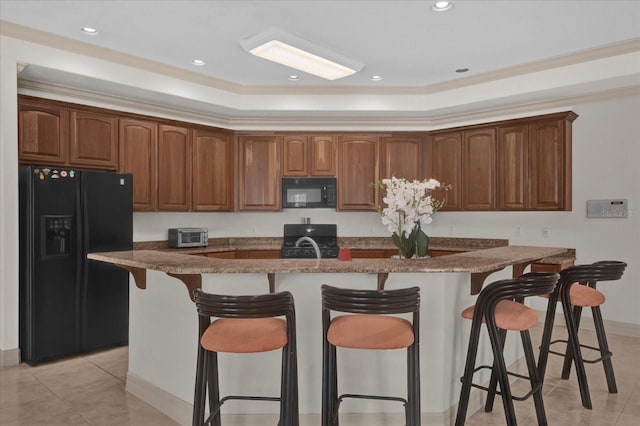 kitchen featuring light tile patterned floors, a kitchen island with sink, a kitchen breakfast bar, ornamental molding, and black appliances