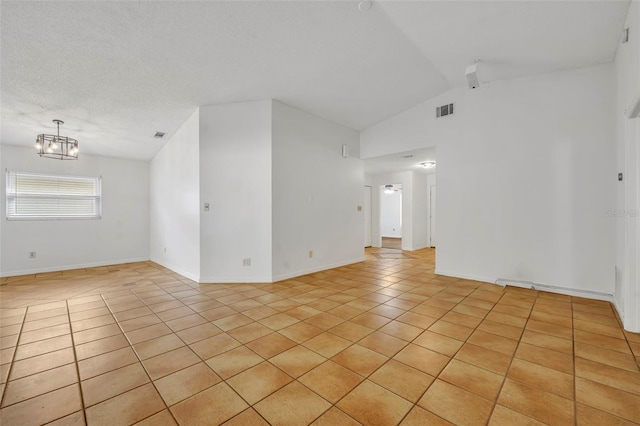 empty room with light tile patterned flooring, vaulted ceiling, a textured ceiling, and a notable chandelier