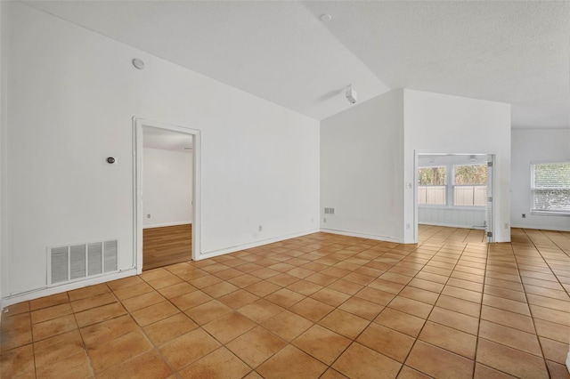 tiled empty room with vaulted ceiling and a textured ceiling