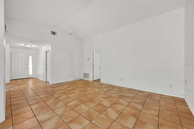 tiled empty room featuring lofted ceiling