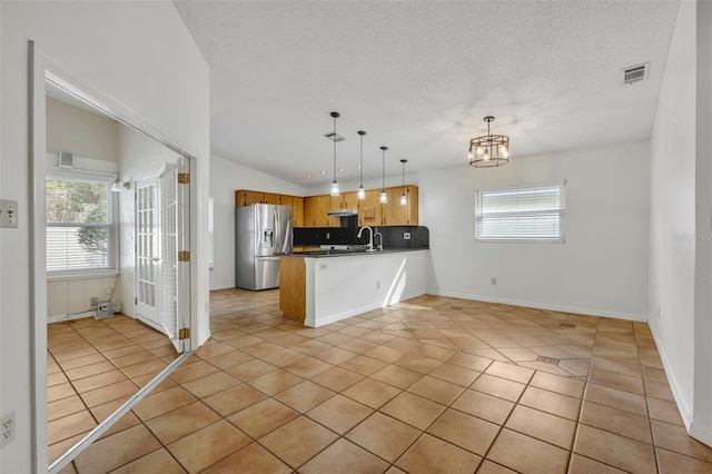 kitchen featuring decorative light fixtures, light tile patterned flooring, kitchen peninsula, and stainless steel refrigerator with ice dispenser