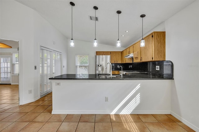 kitchen with pendant lighting, vaulted ceiling, kitchen peninsula, and stainless steel refrigerator with ice dispenser