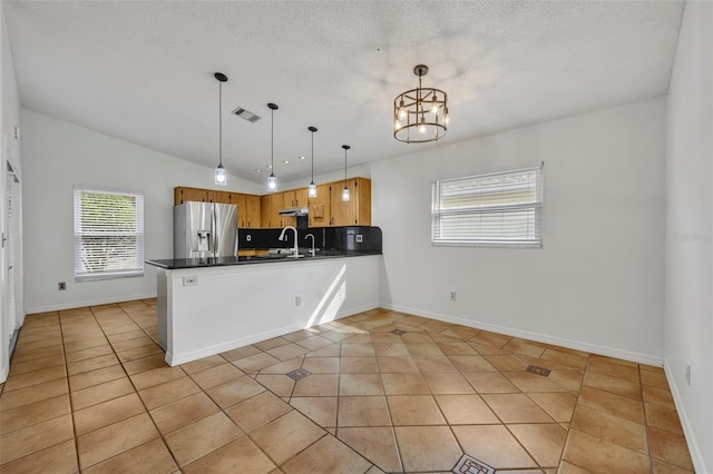 kitchen featuring vaulted ceiling, kitchen peninsula, stainless steel fridge with ice dispenser, and pendant lighting