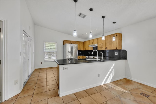 kitchen featuring vaulted ceiling, appliances with stainless steel finishes, decorative light fixtures, and kitchen peninsula