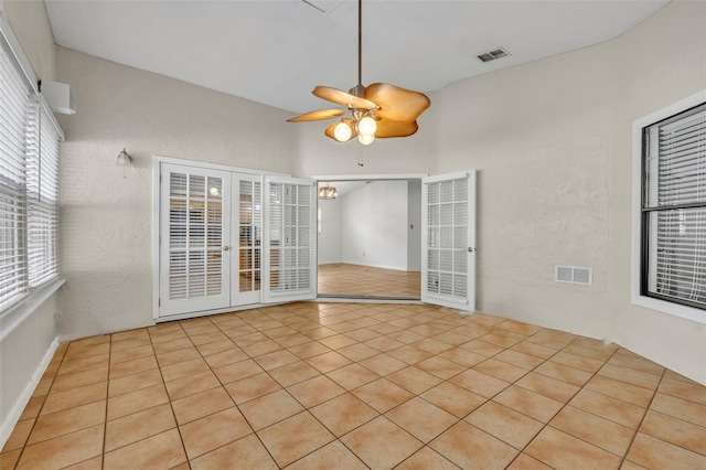 tiled empty room featuring french doors and ceiling fan