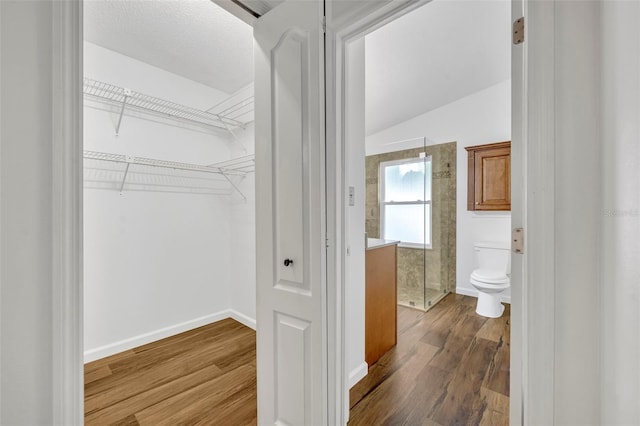 interior space featuring walk in shower, wood-type flooring, toilet, and vaulted ceiling