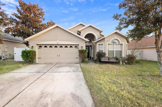 single story home featuring stucco siding, concrete driveway, an attached garage, fence, and a front lawn