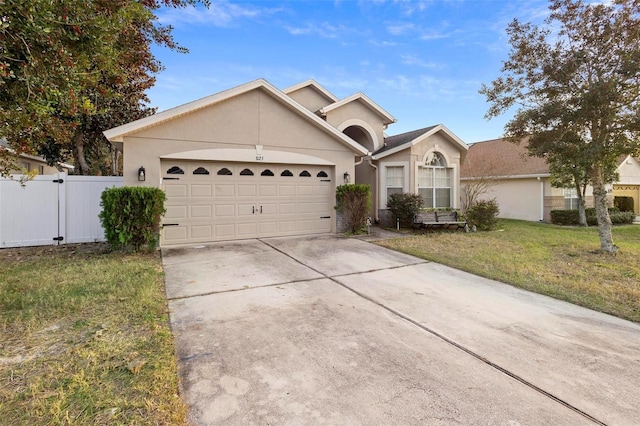 single story home with concrete driveway, an attached garage, a gate, a front lawn, and stucco siding