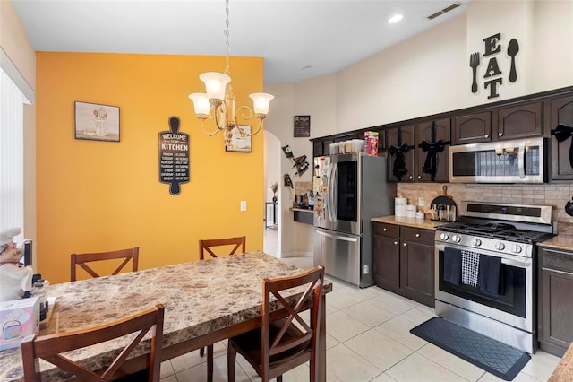 kitchen featuring dark brown cabinetry, stainless steel appliances, a kitchen breakfast bar, hanging light fixtures, and light tile patterned floors