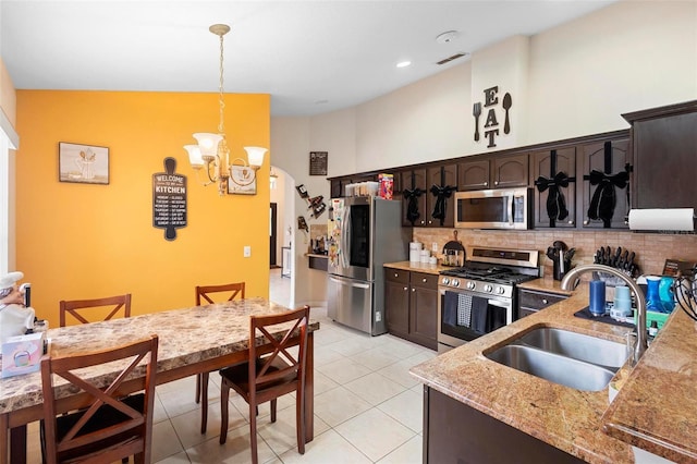 kitchen featuring hanging light fixtures, sink, tasteful backsplash, stainless steel appliances, and dark brown cabinetry