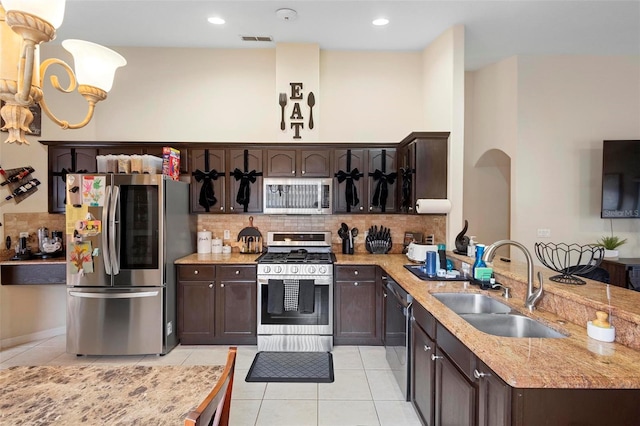 kitchen with sink, dark brown cabinetry, light tile patterned floors, and stainless steel appliances