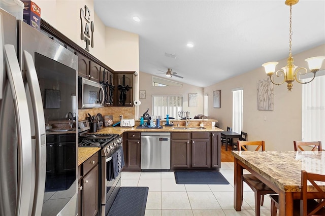 kitchen with pendant lighting, vaulted ceiling, stainless steel appliances, light tile patterned flooring, and dark brown cabinetry