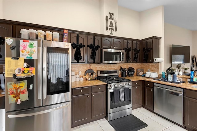 kitchen with light tile patterned floors, backsplash, dark brown cabinetry, and appliances with stainless steel finishes