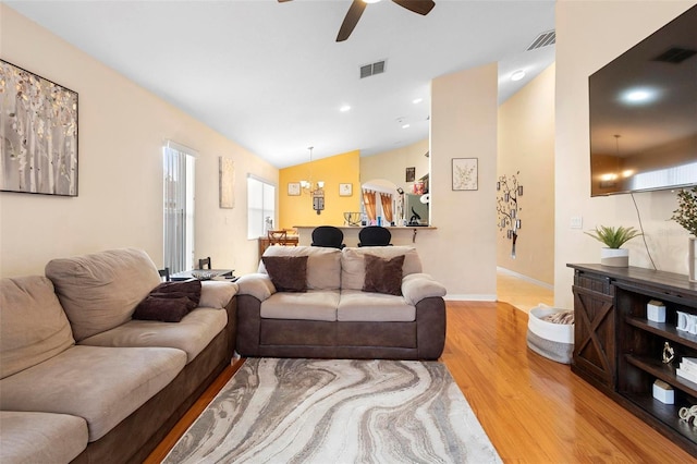 living room with hardwood / wood-style floors, ceiling fan with notable chandelier, and vaulted ceiling