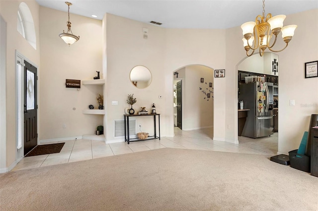 foyer featuring a towering ceiling, light tile patterned floors, and a notable chandelier