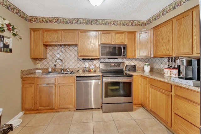 kitchen with light tile patterned flooring, sink, light stone counters, a textured ceiling, and stainless steel appliances