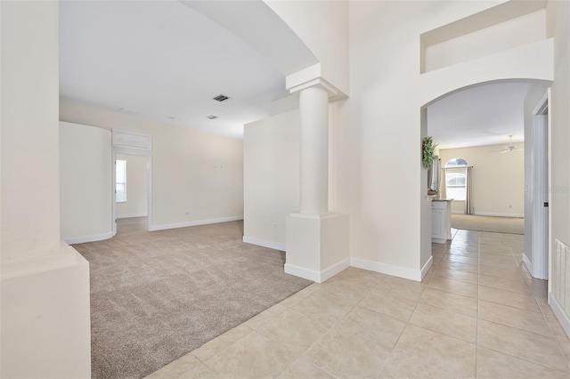 interior space with visible vents, arched walkways, light tile patterned flooring, decorative columns, and light colored carpet