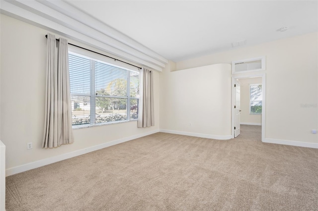 unfurnished room with baseboards and light colored carpet