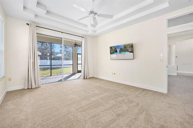 unfurnished room with a raised ceiling, carpet flooring, a ceiling fan, and baseboards