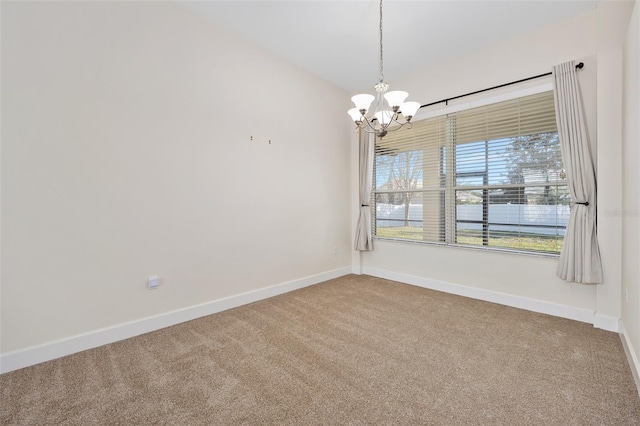 carpeted spare room with baseboards and a chandelier