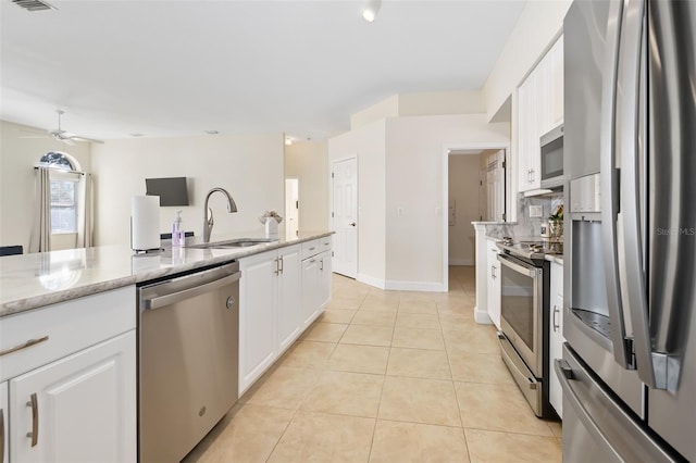 kitchen with a sink, stainless steel appliances, light tile patterned flooring, and white cabinetry