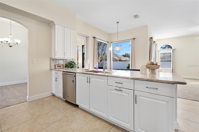 kitchen featuring a sink, light stone countertops, light colored carpet, hanging light fixtures, and stainless steel dishwasher