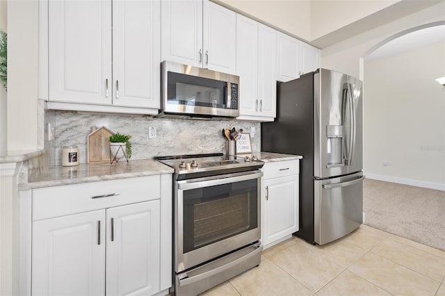 kitchen with light carpet, light tile patterned floors, decorative backsplash, stainless steel appliances, and white cabinetry