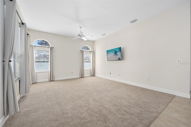 spare room with visible vents, baseboards, light colored carpet, and a healthy amount of sunlight