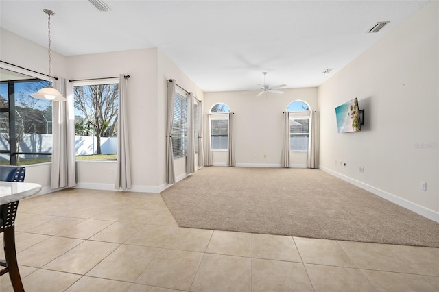 interior space featuring tile patterned floors, visible vents, baseboards, and a ceiling fan