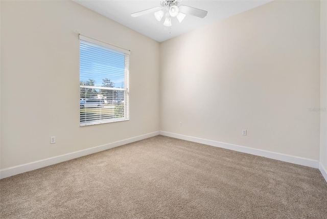 empty room with light colored carpet, baseboards, and ceiling fan