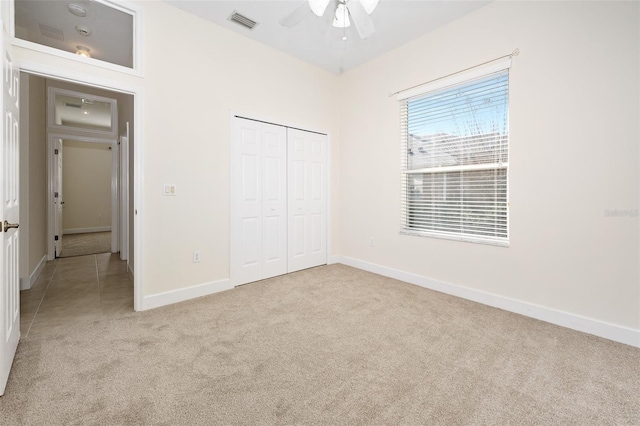 unfurnished bedroom featuring visible vents, baseboards, light carpet, a closet, and a ceiling fan