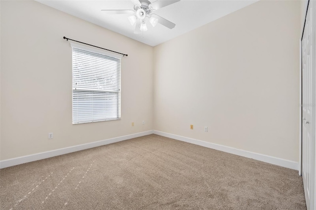 carpeted spare room with baseboards and ceiling fan