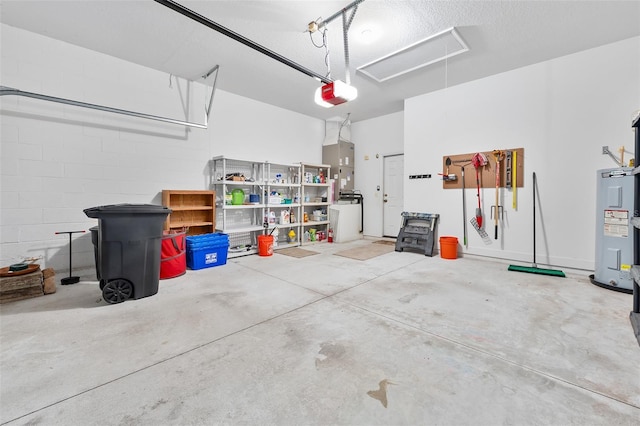 garage with concrete block wall, a garage door opener, and electric water heater