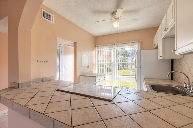 kitchen with decorative backsplash, sink, white cabinets, and tile counters