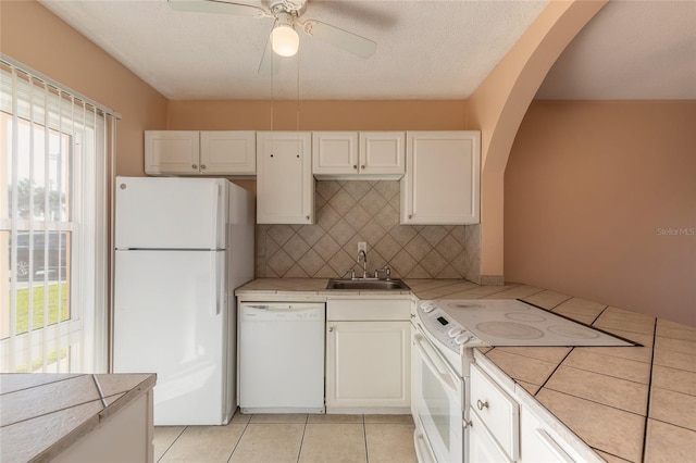 kitchen featuring white appliances, light tile patterned floors, decorative backsplash, white cabinets, and sink