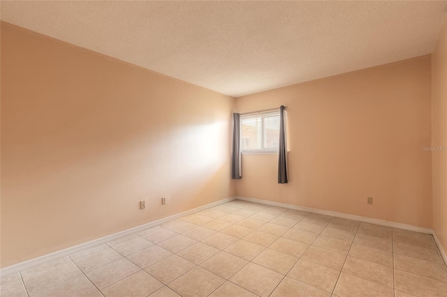 tiled empty room featuring a textured ceiling