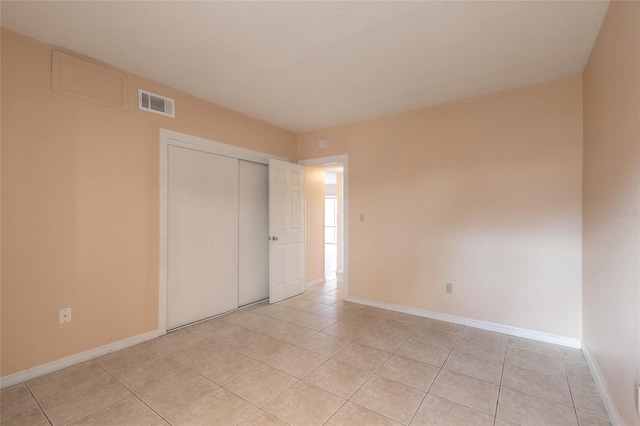 unfurnished bedroom with light tile patterned flooring and a closet