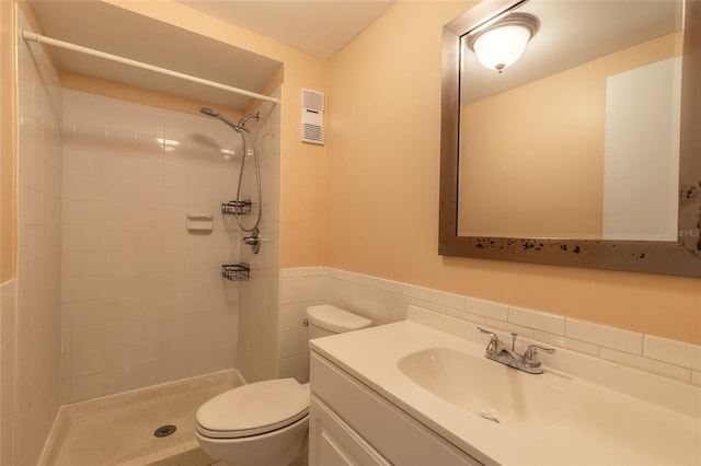 bathroom with tile walls, toilet, tiled shower, and vanity