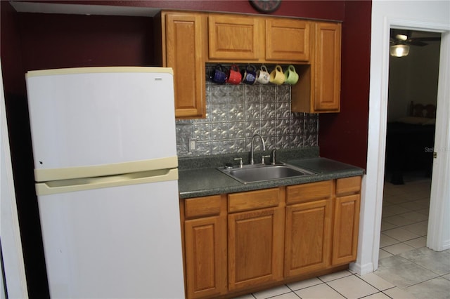 kitchen with sink, light tile patterned floors, white fridge, and tasteful backsplash