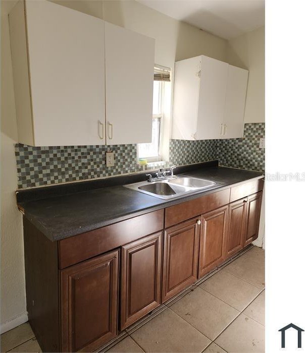 kitchen with light tile patterned flooring, sink, and backsplash